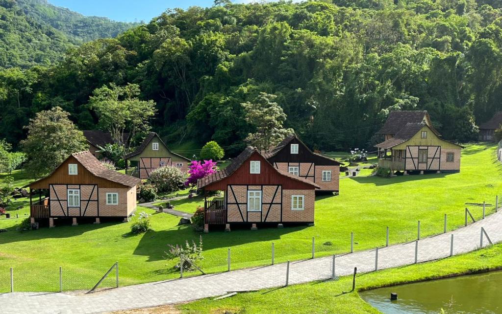 a group of houses on a green field with a river at Paraíso Enxaimel Mundo Antigo in Pomerode