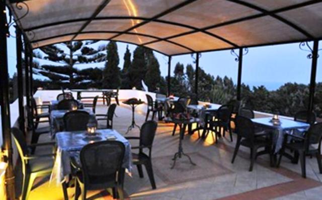 a patio area with tables, chairs and umbrellas at B&B Il Giardino Segreto in Stromboli