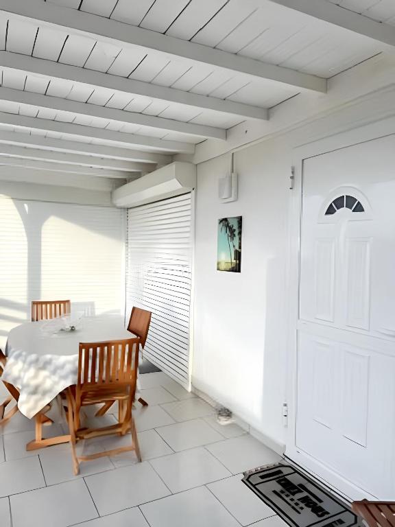 a white dining room with a table and chairs at Appartement charmant Deshaies vue mer in Deshaies