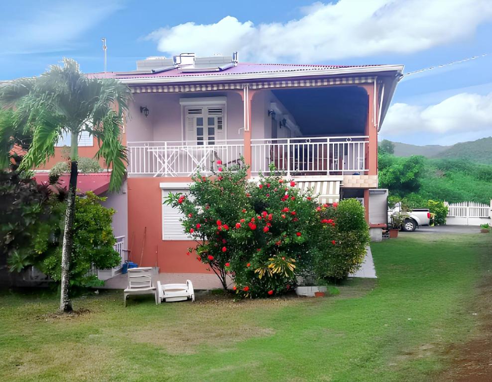 a pink house with a balcony and a palm tree at Studio charmant à Sainte-Luce, 28 m², terrasse et jardin. in Sainte-Luce