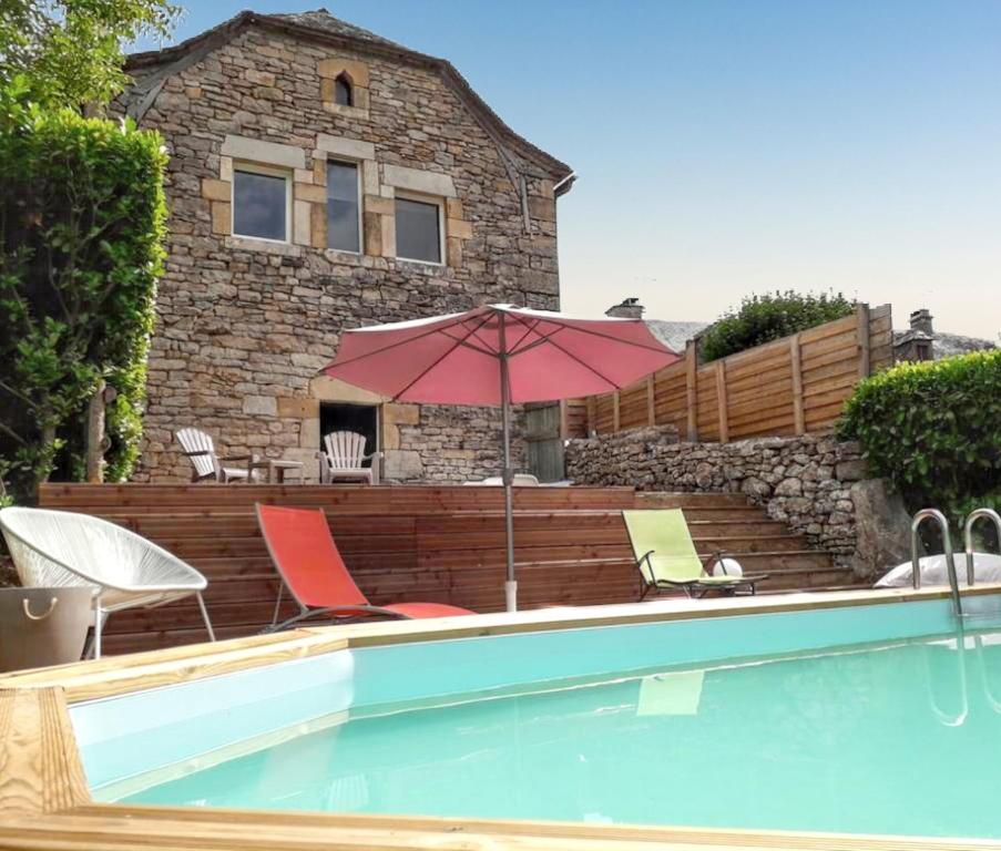 einem Pool mit Stühlen und einem Sonnenschirm vor einem Haus in der Unterkunft Maison de caractère à Pierrefiche avec piscine privée in Pierrefiche