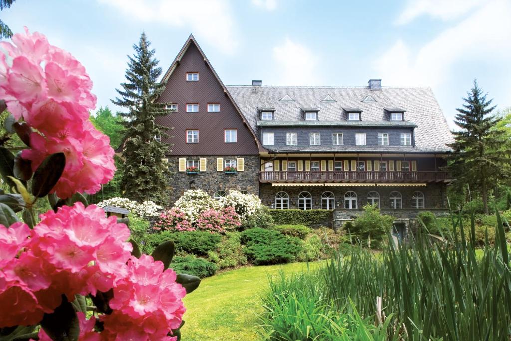 een groot huis met roze bloemen ervoor bij Romantik Hotel Jagdhaus Waldidyll in Hartenstein