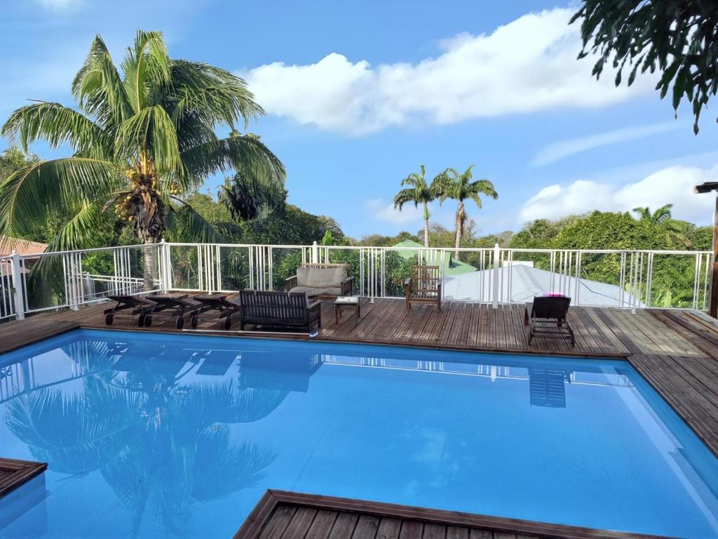 une piscine avec une terrasse, des chaises et des palmiers dans l'établissement Maison spacieuse à Pointe-Noire avec piscine partagée 110 m², à Pointe-Noire