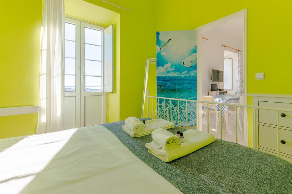 a bedroom with yellow walls and a bed with towels at Alfama Santa Apolonia Apartment in Lisbon
