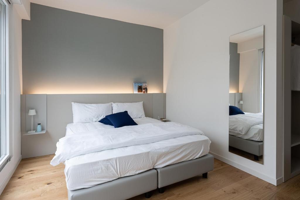 una camera da letto con un grande letto bianco e uno specchio di Casa Kaleido a Trento
