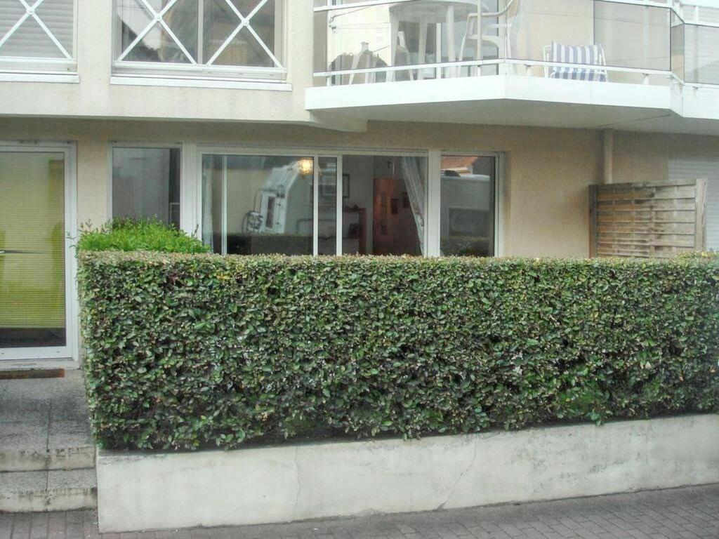 une haie en face d'une maison avec balcon dans l'établissement Appartement moderne au Touquet-Paris-Plage, jardin clôturé, à Le Touquet-Paris-Plage