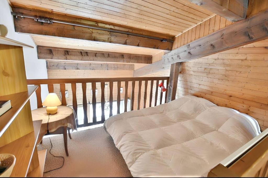 a bed in a room with a wooden wall at Appartement cosy à Samoëns de 57 m² avec balcon. in Samoëns