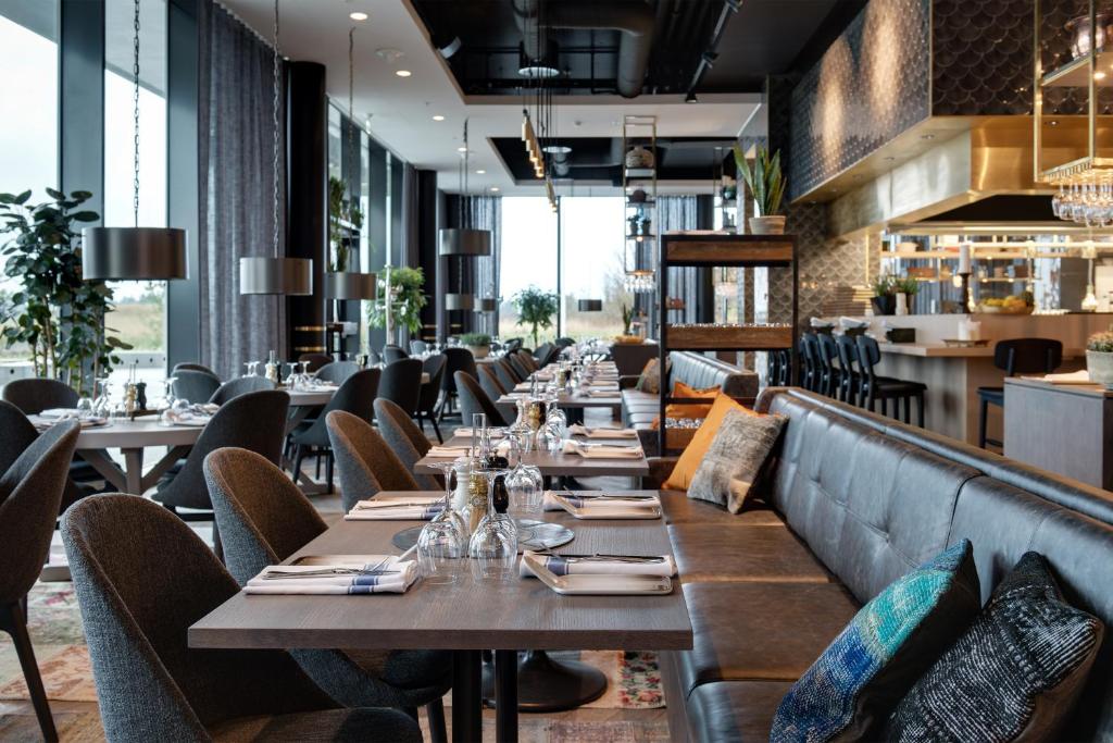 a restaurant with wooden tables and chairs and a bar at Clarion Hotel Air in Sola