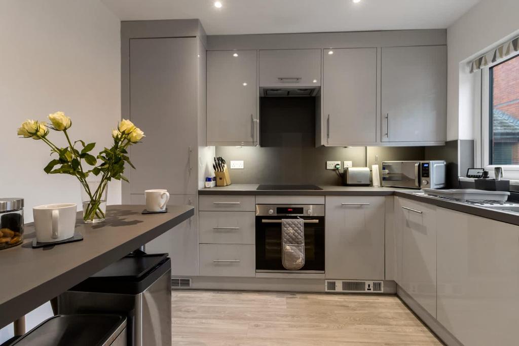 a kitchen with white cabinets and stainless steel appliances at Quay Escape - Short Stays UK Ltd in Exeter