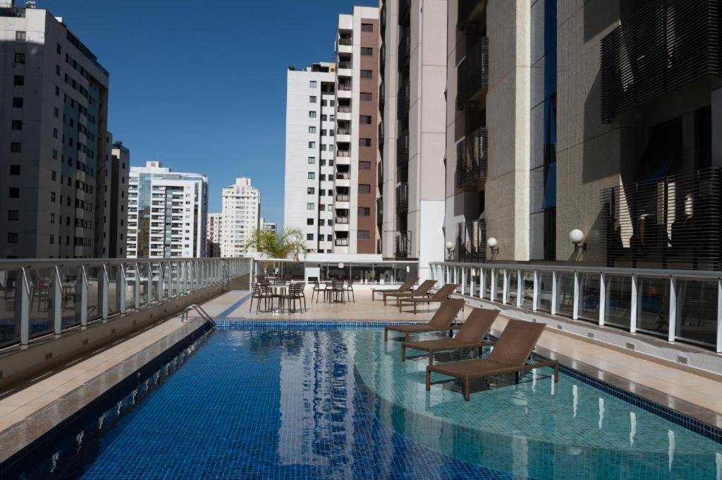 a swimming pool with chairs and tables on a building at Flat S4 Hotel - Águas Claras - Brasília in Brasilia