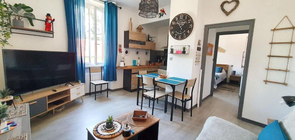 un salon avec une télévision, une table et des chaises dans l'établissement Charmant appartement à Carcassonne avec vue sur le jardin - 35m², à Carcassonne
