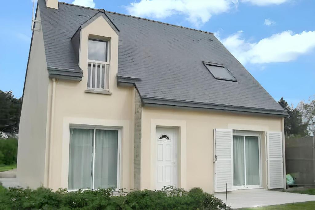 une maison blanche avec un toit noir dans l'établissement Maison charmante à Perros-Guirec avec terrasse et jardin, à Perros-Guirec