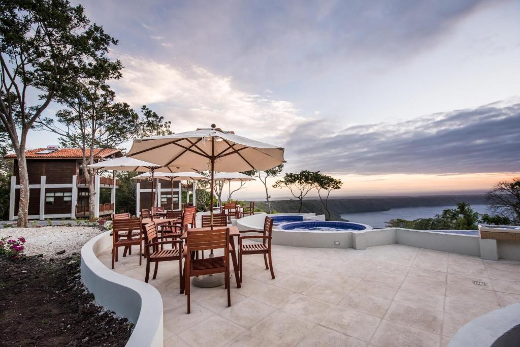 een patio met een tafel en stoelen en een parasol bij Pacaya Lodge and Spa in La Laguna