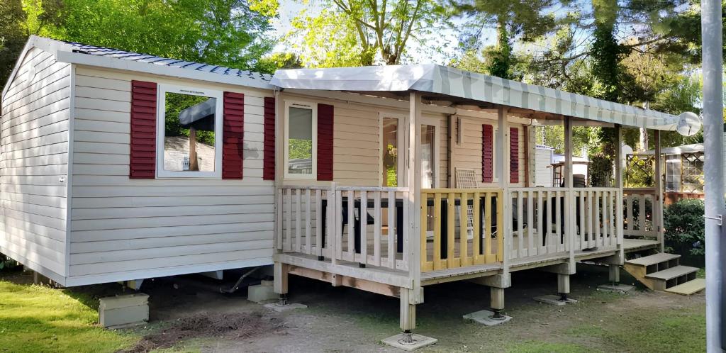 une petite maison avec une terrasse couverte et des touches de rouge dans l'établissement Bungalow chaleureux à Saint-Jean-de-Monts avec piscine partagée., à Saint-Jean-de-Monts