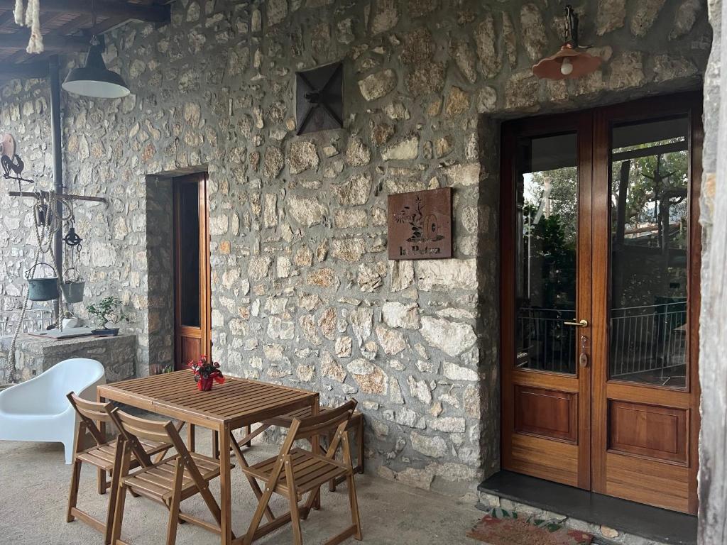 a wooden table and chairs in front of a stone wall at La Petra in Vico Equense