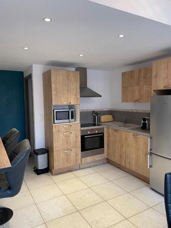 une cuisine avec des armoires en bois et un réfrigérateur dans l'établissement Appartement la Cayolle, à Barcelonnette