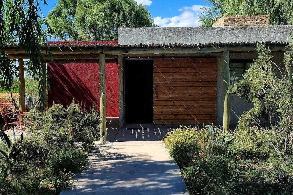 a red building with a door in a garden at Casa H entre viñedos in Ciudad Lujan de Cuyo