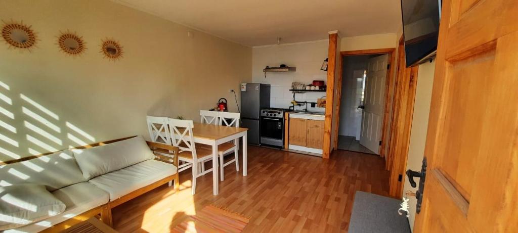 Una sala de estar con un sofá y una mesa y una cocina. en Cabañas junto a la playa, en Las Cruces