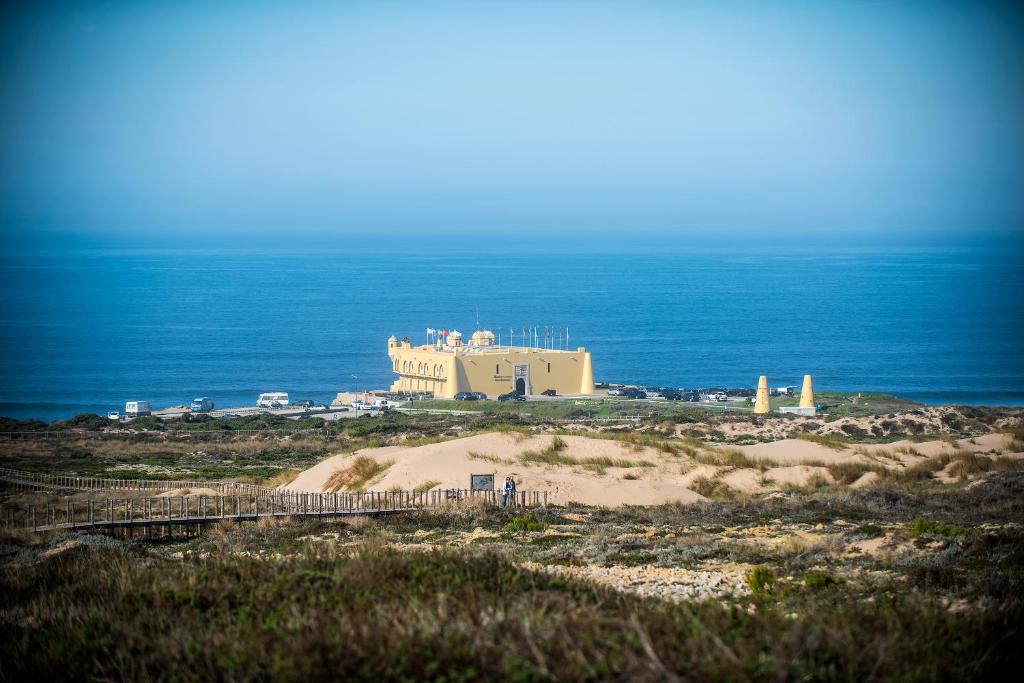 a building on a beach with the ocean in the background at Hotel Fortaleza do Guincho Relais & Châteaux in Cascais