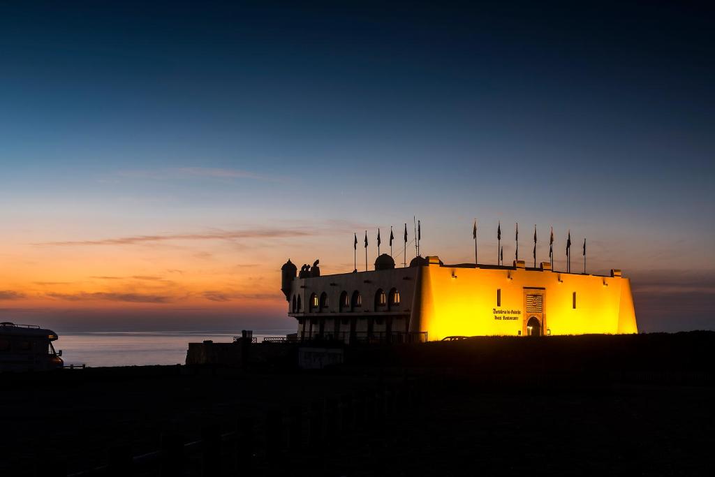 a building is lit up in the sunset at Hotel Fortaleza do Guincho Relais & Châteaux in Cascais