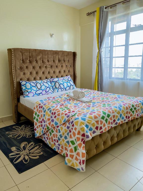a bedroom with a bed with a colorful comforter and a window at Executive 1 bedroom house in Nairobi