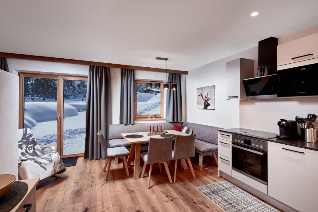 a kitchen and living room with a table and chairs at Chalet Buchensteinwand Luxusapartment mit Sauna am Berg in Sankt Ulrich am Pillersee