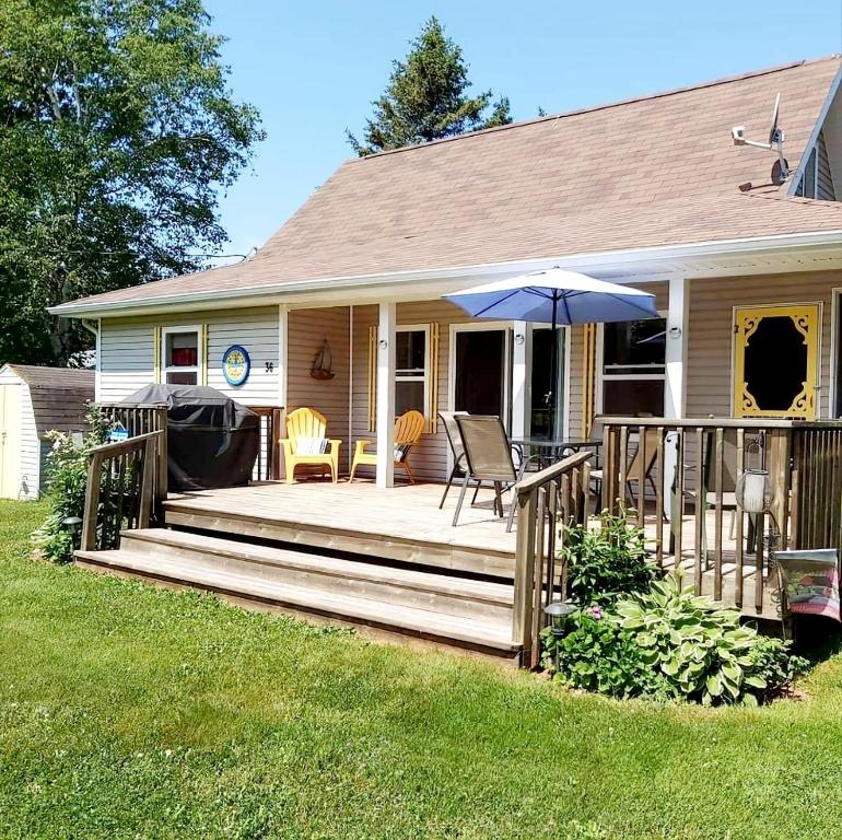 a house with a wooden deck with an umbrella at Little Eden Summer Beach Home in Long Creek
