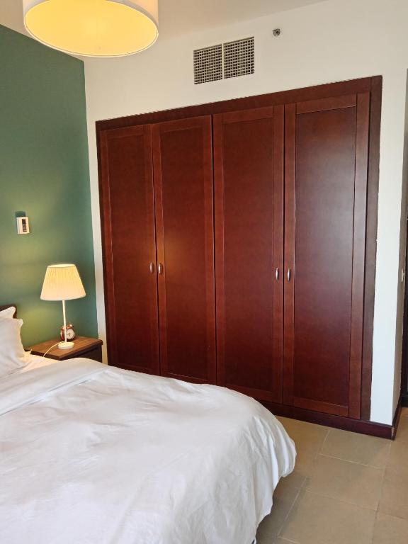 King Abdullah Economic Cityにあるجوهرة أبراج المارينا Jawhara Al Marinaの大きなベッドと木製のキャビネットを備えた寝室