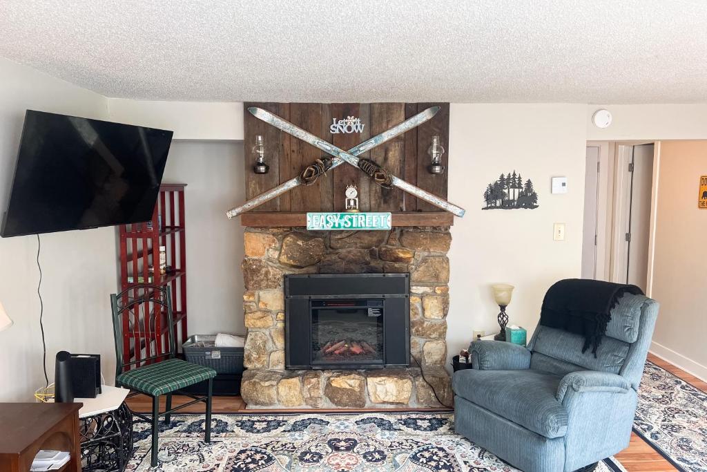un salon avec une cheminée en pierre et une télévision dans l'établissement Easy Street Retreat, à Sugar Mountain