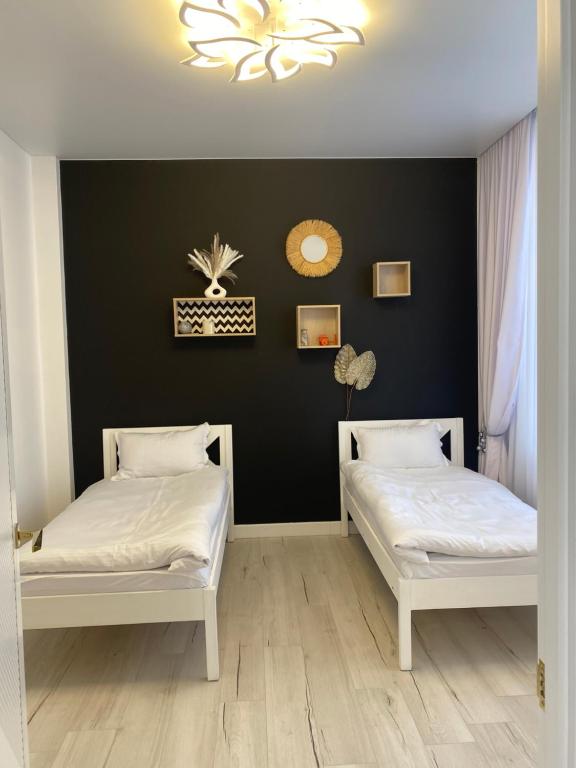 two beds in a room with a black wall at Шикарный Гостевой Guest Аpartments MURAGER in Astana