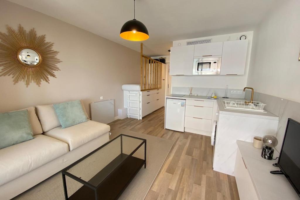 un salon avec un canapé et une cuisine dans l'établissement 06AI - Beautiful renovated studio - sea and pool view, à Vallauris