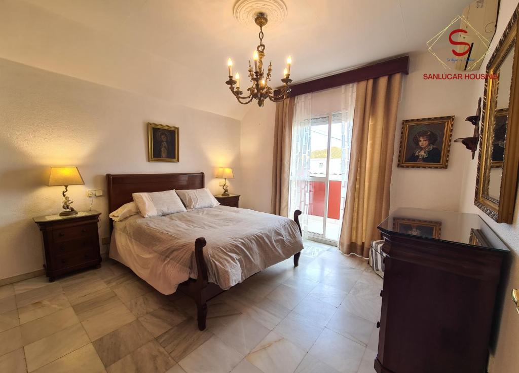 una camera da letto con un letto e un lampadario di Casa Hermosilla con piscina by Sanlúcar Housing a Sanlúcar de Barrameda