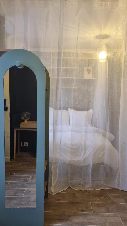 - une chambre avec un lit avec des draps blancs et une table dans l'établissement Studio bleu pleyel, à Saint-Denis