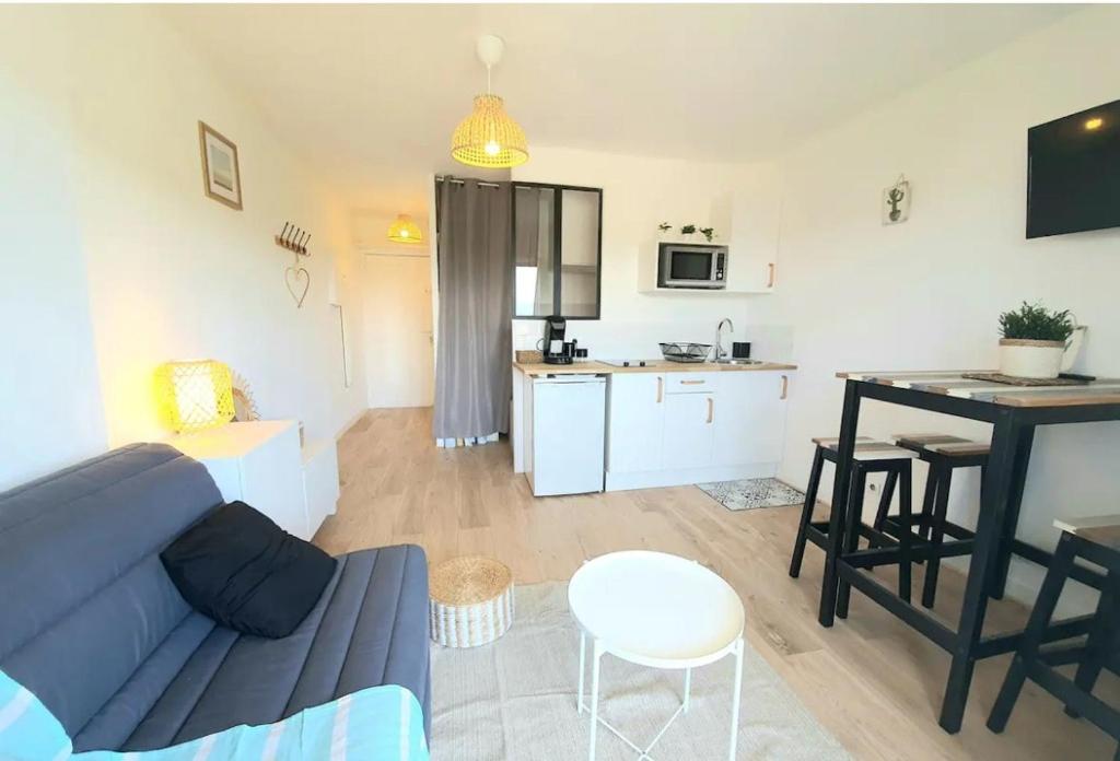 un salon avec un canapé bleu et une cuisine dans l'établissement Appartement à 500m de la plage, à Canet