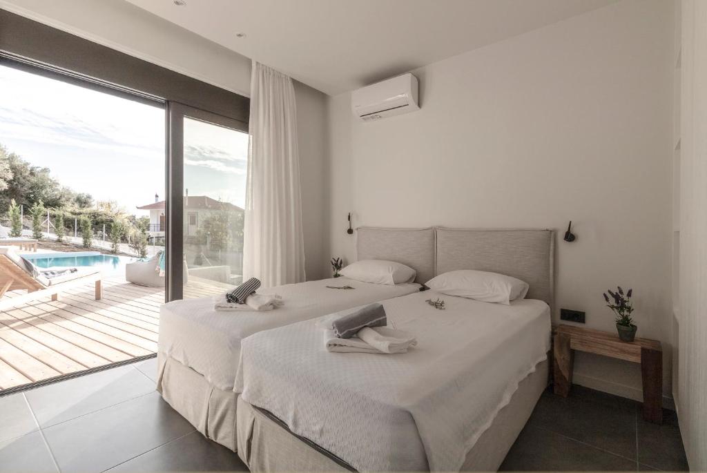 een slaapkamer met twee bedden en een groot raam bij Villa Oneiro in Paleros