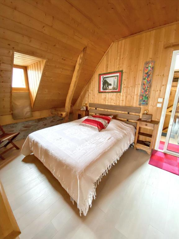 une chambre avec un lit dans une cabane en rondins dans l'établissement Maison chaleureuse à Mont >Vue montagne & cheminée, à Mont
