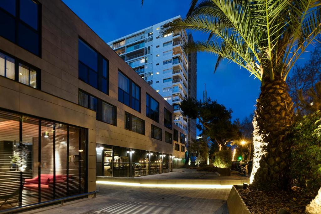 a palm tree in front of a building at night at Upper Diagonal in Barcelona