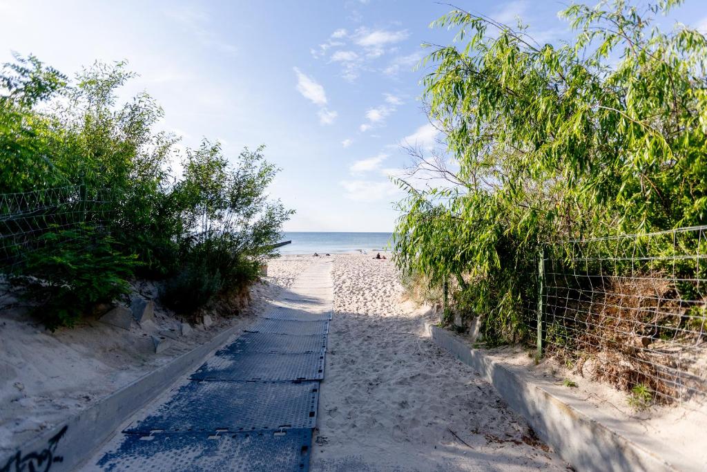 un chemin menant à la plage bordé d'arbres et de l'océan dans l'établissement Apartament YAGI z bezpłatnym parkingiem Dziwnówek nad morzem EPapartamenty, à Dziwnówek