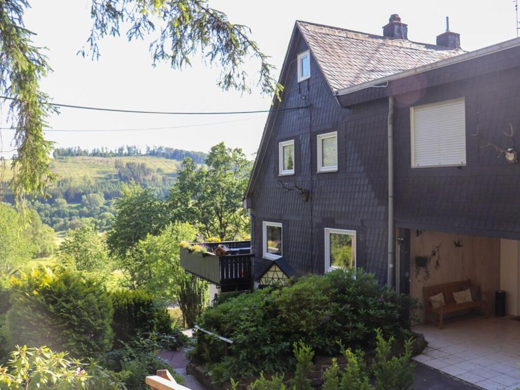 a black house with a porch and a balcony at The Waldhaus Modern retreat in Neerdar