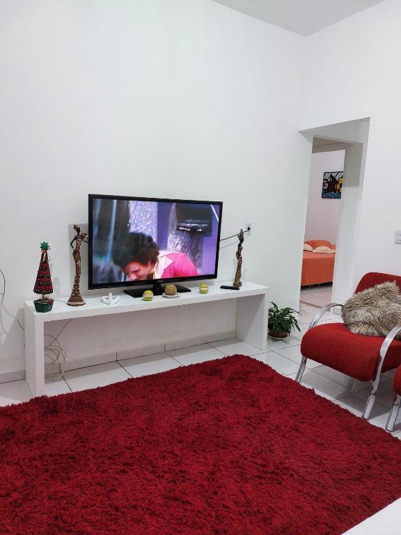 a living room with a tv and a red rug at Porto Belo Perequê in Porto Belo