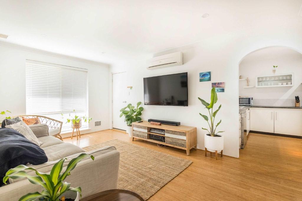 a living room with a couch and a flat screen tv at Sunset Villa Scarborough in Perth