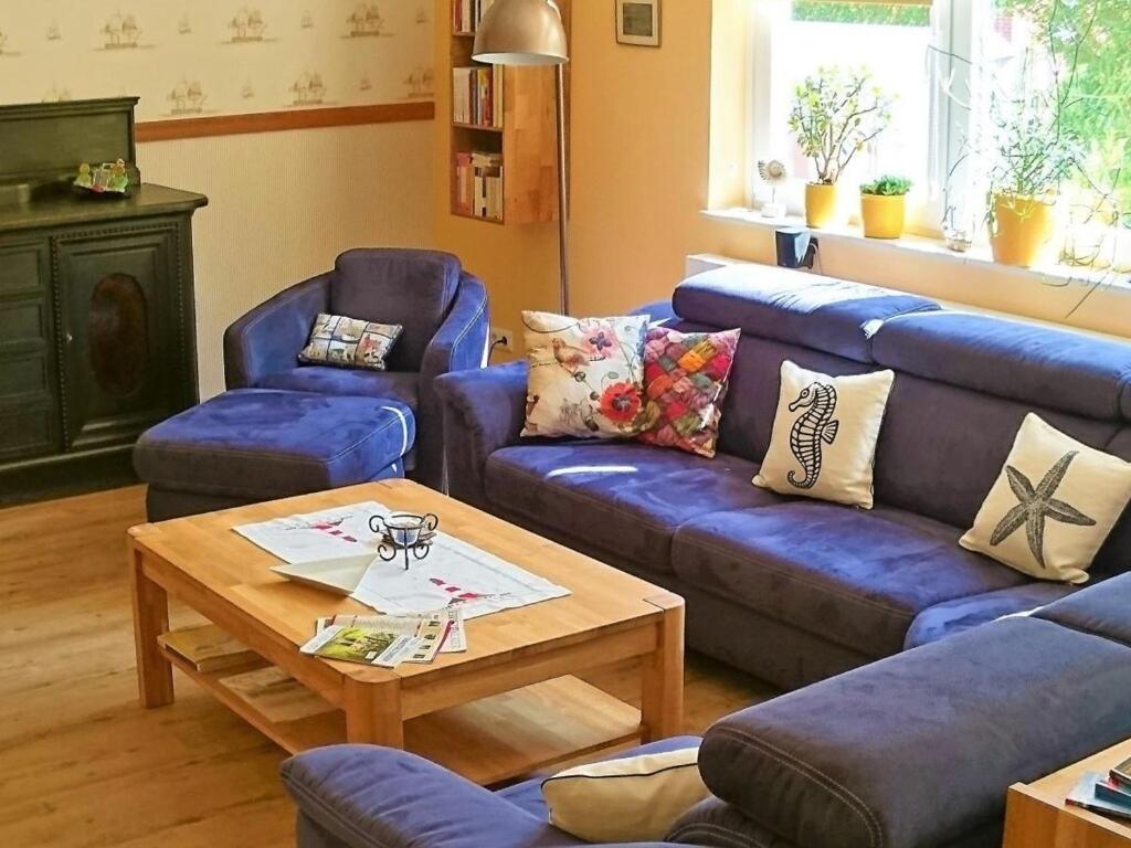 a living room with blue couches and a coffee table at Tönnihuus Comfortable holiday residence in Tönning