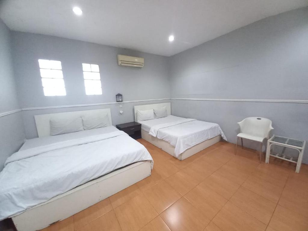 バンドンにあるHotel Patradissa Stasiun Bandungのベッド2台と椅子が置かれた寝室