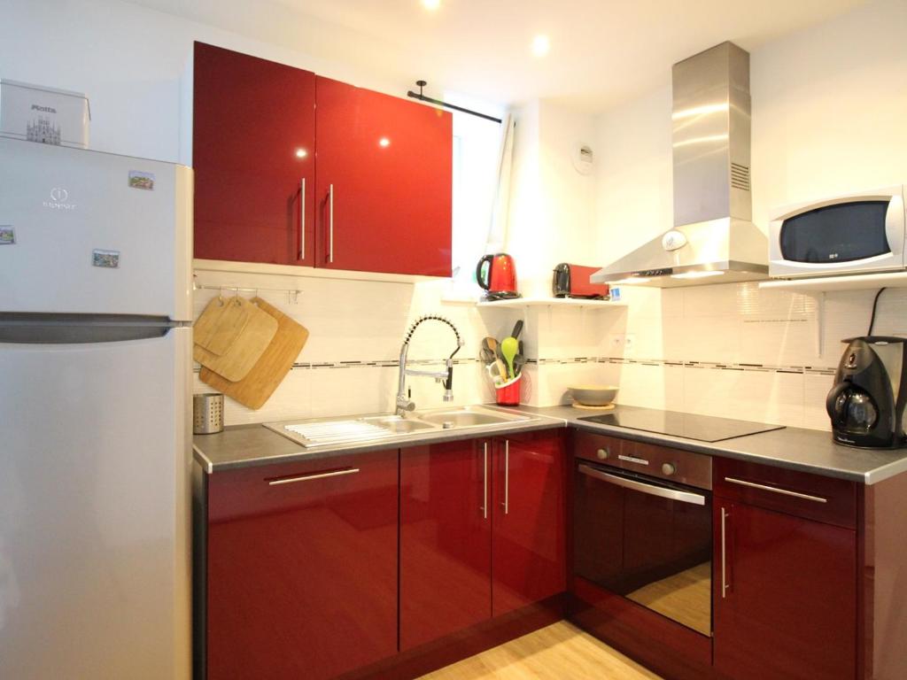 une cuisine avec des armoires rouges et un réfrigérateur blanc dans l'établissement Bel F4 au 2ème étage sans ascenseur, centre Mont-Dore, 3 chambres, bien équipé, capacité 6 pers - FR-1-415-24, à Le Mont-Dore