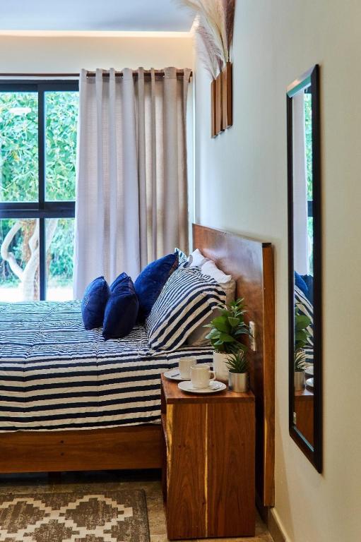 a bedroom with a bed with blue pillows and a window at Infinity Pool rooftop wifi Tulum in Tulum