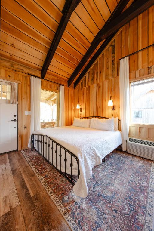 a bedroom with a bed in a wooden room at Peaceful Creekside Tiny Cabin, Family Adventure Near Waterfalls in Smithville
