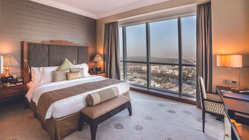 a bedroom with a large bed and large windows at Dusit Thani Abu Dhabi in Abu Dhabi