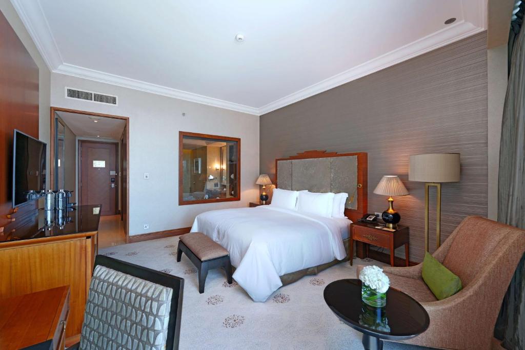 a hotel room with a large bed and a television at Dusit Thani Abu Dhabi in Abu Dhabi
