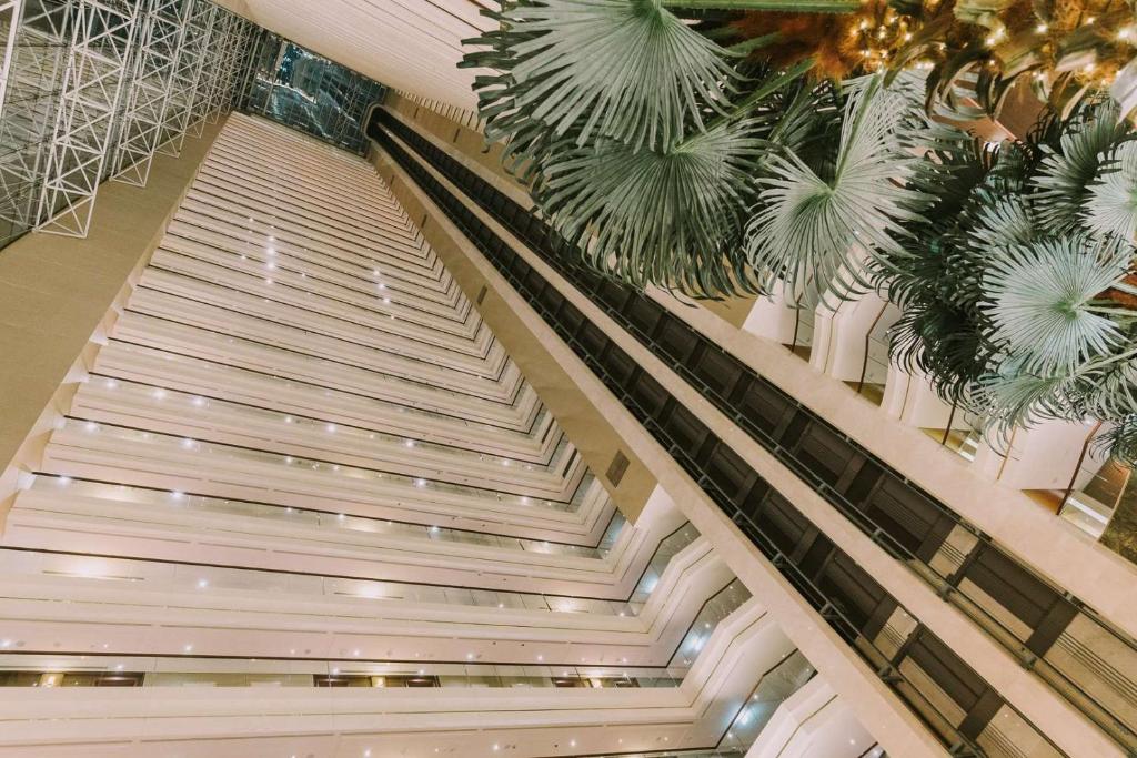 an escalator in a building with palm trees at Dusit Thani Abu Dhabi in Abu Dhabi