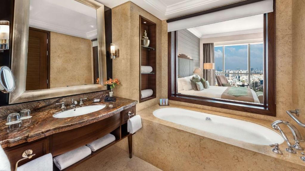 a bathroom with a tub and a large mirror at Dusit Thani Abu Dhabi in Abu Dhabi